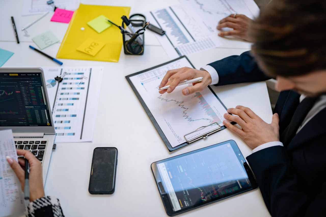 Équipe examinant des graphiques financiers et des données numériques sur des tablettes dans un cadre de bureau.